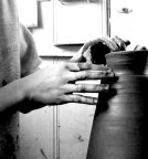 Gros plan sur des mains travaillant la terre sur un tour de poterie dans un atelier de céramique.
