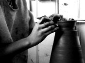 Gros plan sur des mains travaillant la terre sur un tour de poterie dans un atelier de céramique.